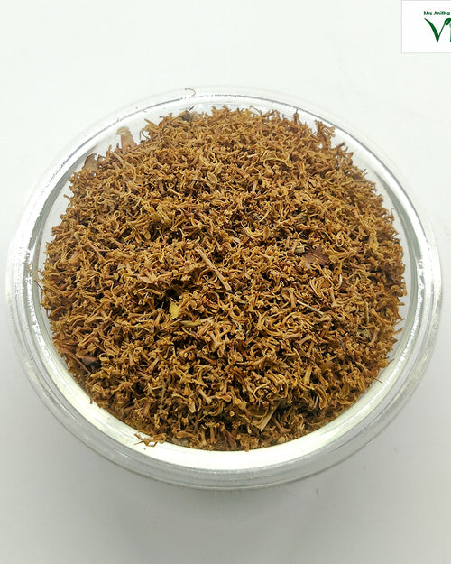 Veppam Poo, a clear round bowl filled with brown dried flower fragments and tiny twigs viewed from above against a white background