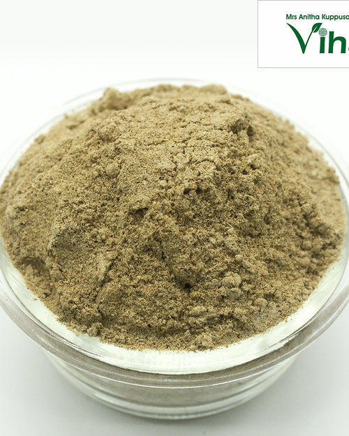 Vettiver Powder, a mound of fine brownish-grey fibrous powder in a transparent round glass bowl against a white background