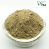 Vettiver Powder, a mound of fine brownish-grey fibrous powder in a transparent round glass bowl against a white background