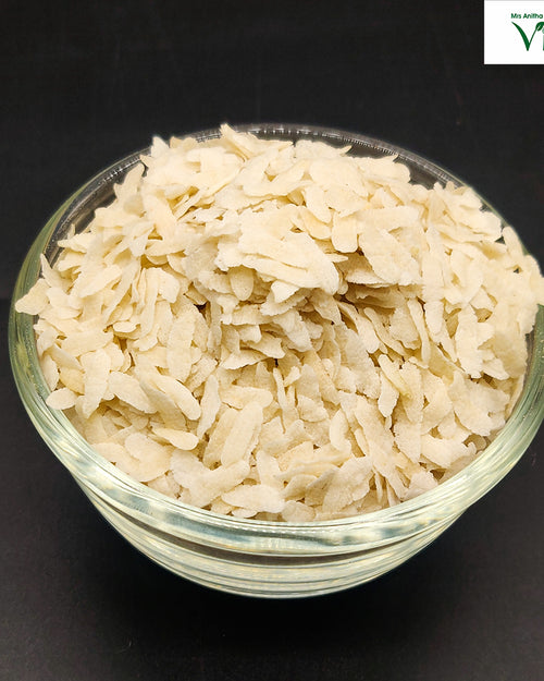 White Poha/Aval, in a squat glass bowl of dried flakes